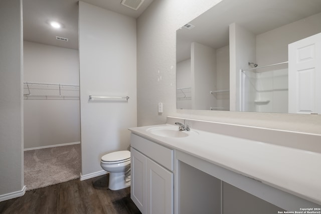 bathroom featuring a shower, hardwood / wood-style floors, vanity, and toilet