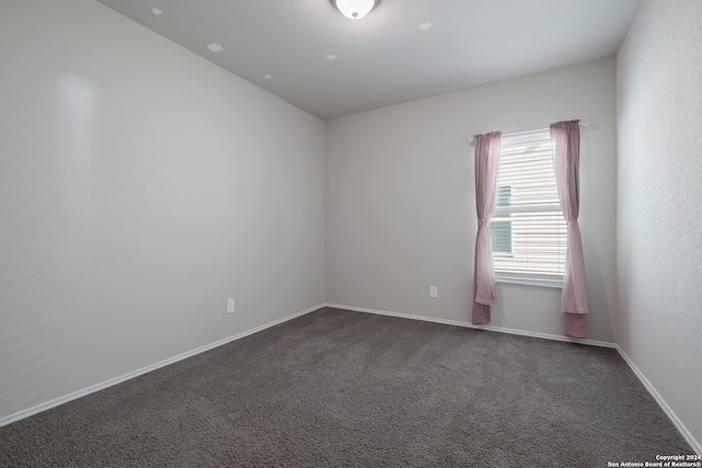 unfurnished room with dark carpet