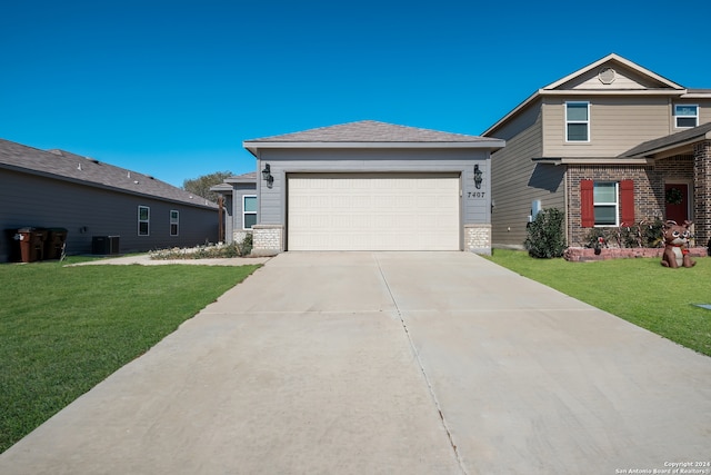 view of front of property featuring central air condition unit, a front yard, and a garage