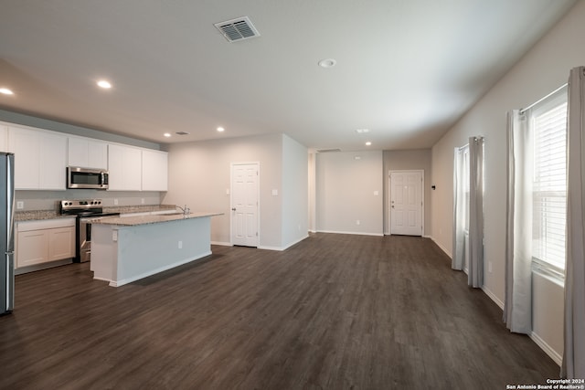 kitchen featuring dark wood-type flooring, a center island with sink, sink, appliances with stainless steel finishes, and white cabinetry