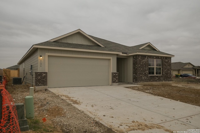 ranch-style home with brick siding, board and batten siding, central AC, a garage, and driveway