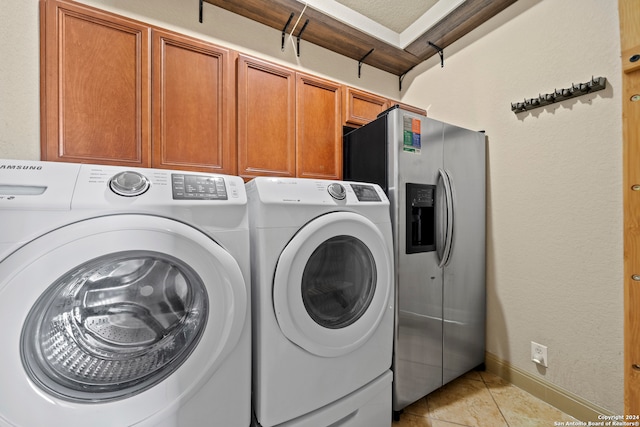 laundry area featuring washer and clothes dryer, light tile patterned floors, and cabinets