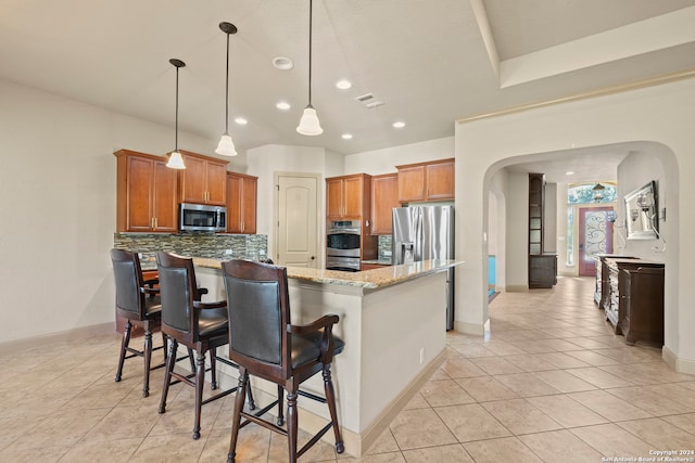 kitchen with decorative backsplash, a kitchen breakfast bar, light stone counters, stainless steel appliances, and pendant lighting