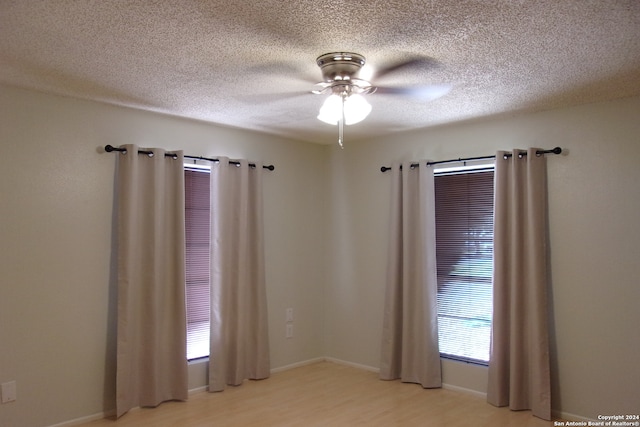 unfurnished room featuring ceiling fan, a textured ceiling, and light wood-type flooring