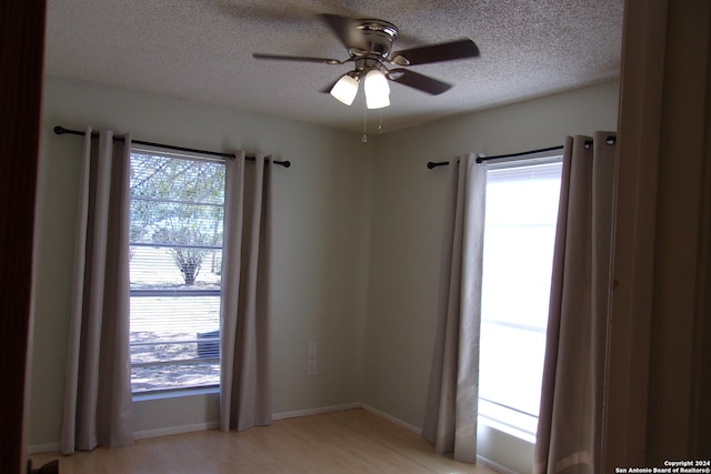 spare room with a textured ceiling, light wood-type flooring, and ceiling fan