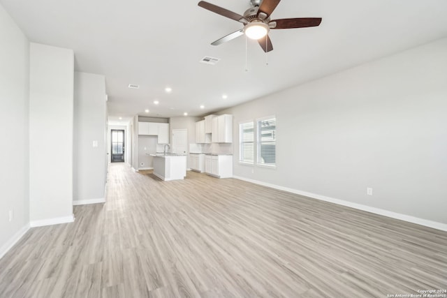 unfurnished living room with light wood-type flooring, ceiling fan, and sink