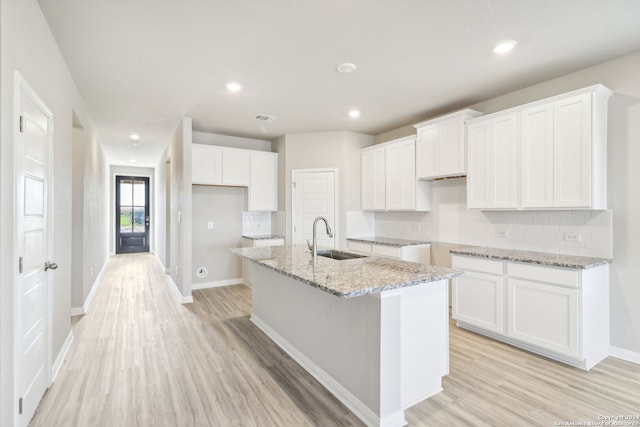 kitchen with white cabinetry, a kitchen island with sink, and light wood-type flooring