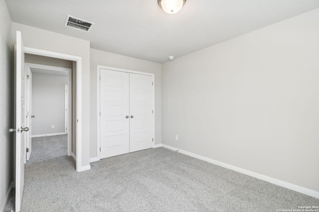 unfurnished bedroom featuring light carpet and a closet