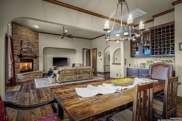 dining area featuring a fireplace, ceiling fan, crown molding, and dark wood-type flooring