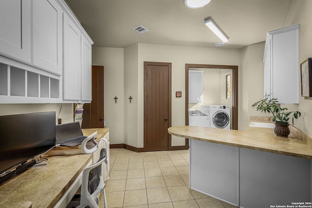 kitchen featuring light tile patterned floors, built in desk, white cabinetry, and washer and clothes dryer