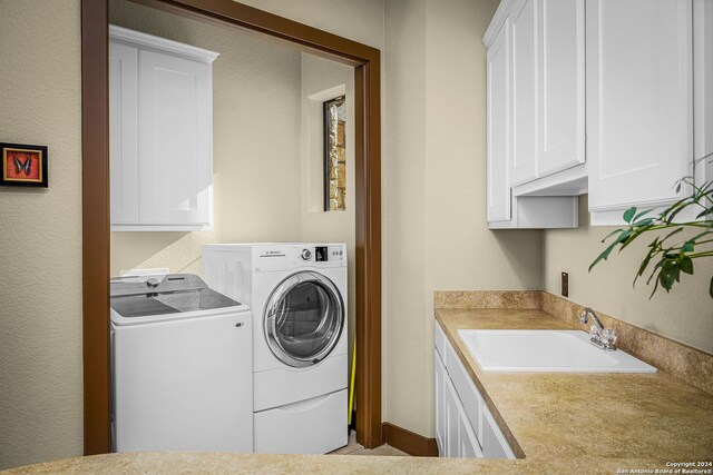 washroom featuring cabinets, sink, and washing machine and clothes dryer