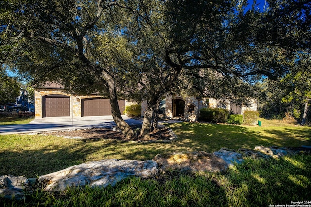 view of property hidden behind natural elements with a garage and a front yard