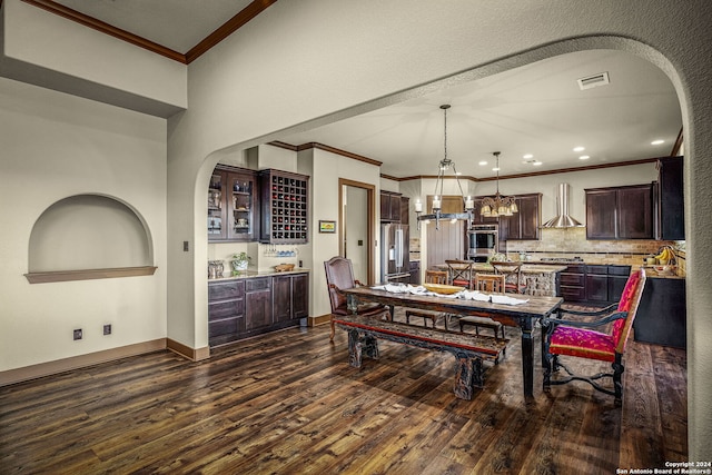 dining room featuring a textured ceiling, ornamental molding, dark wood-type flooring, and a chandelier