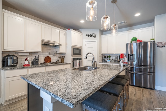 kitchen with a center island with sink, dark hardwood / wood-style floors, stainless steel appliances, and tasteful backsplash