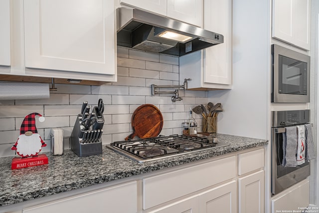 kitchen featuring white cabinets, decorative backsplash, stainless steel appliances, and exhaust hood