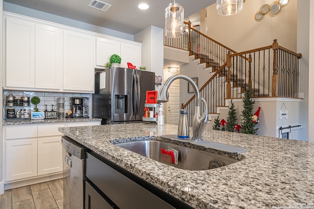 kitchen featuring stainless steel appliances, white cabinetry, hanging light fixtures, and sink