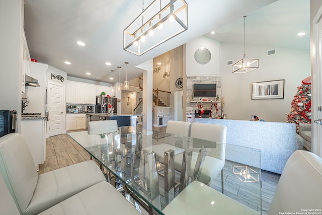 dining space with a fireplace, light hardwood / wood-style floors, vaulted ceiling, and sink