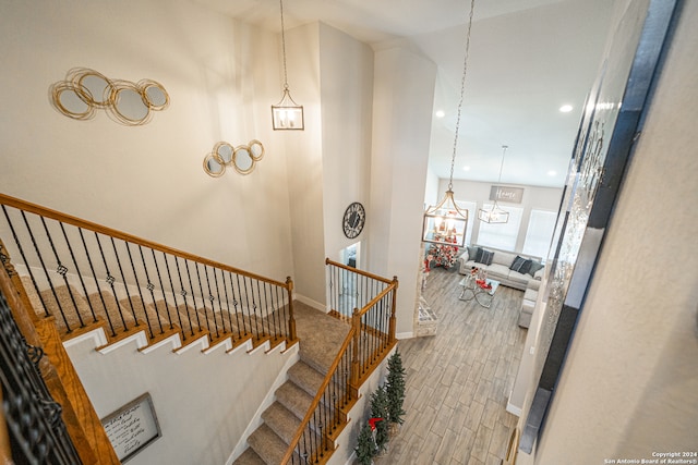 stairway featuring hardwood / wood-style floors, a towering ceiling, and a notable chandelier