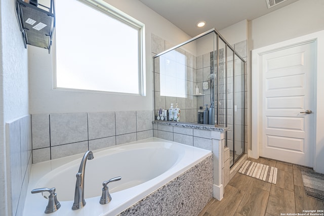 bathroom with a wealth of natural light, hardwood / wood-style floors, and independent shower and bath