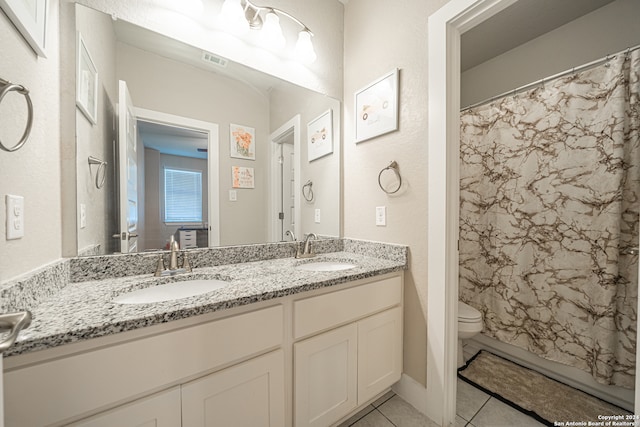 bathroom with toilet, vanity, and tile patterned floors