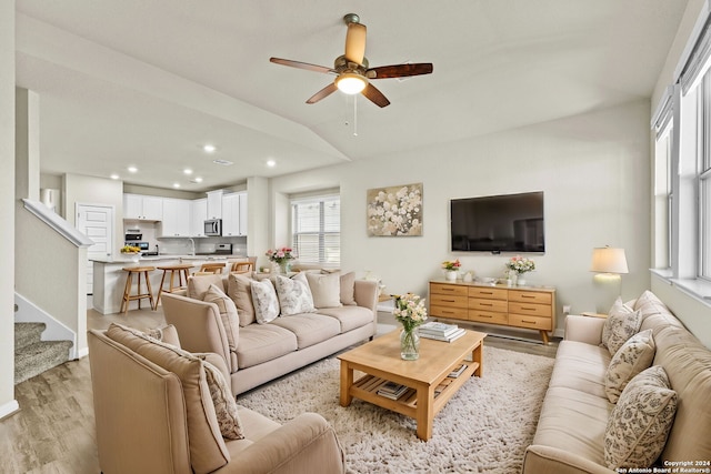 living room featuring ceiling fan, vaulted ceiling, and light hardwood / wood-style flooring