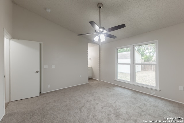 carpeted empty room with a textured ceiling, ceiling fan, and lofted ceiling