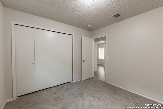 unfurnished bedroom featuring a closet, light colored carpet, and a textured ceiling