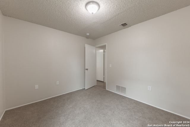 carpeted empty room featuring a textured ceiling