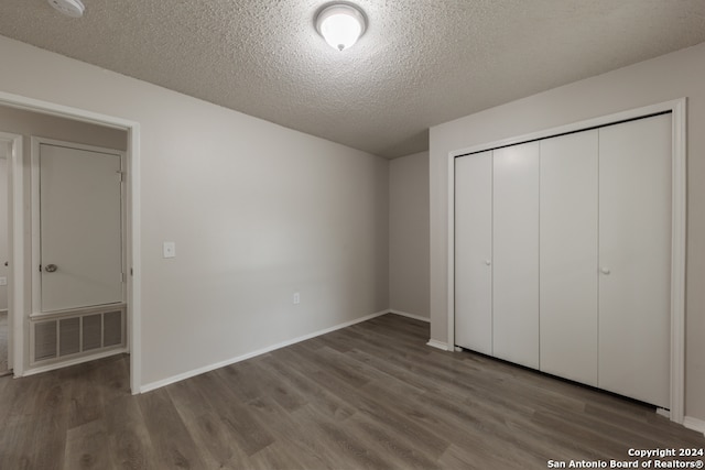 unfurnished bedroom with a textured ceiling, hardwood / wood-style flooring, and a closet