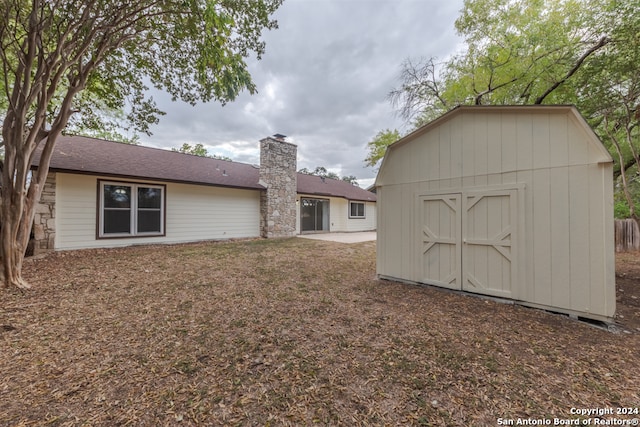 rear view of property with a storage shed