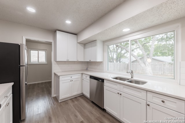 kitchen featuring appliances with stainless steel finishes, white cabinetry, a wealth of natural light, and sink