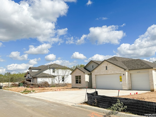 view of front of property featuring fence, concrete driveway, roof with shingles, a garage, and stone siding