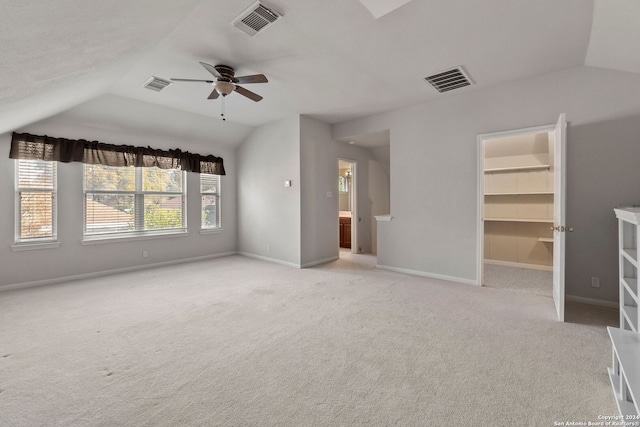 unfurnished bedroom with a walk in closet, ceiling fan, a closet, and light colored carpet