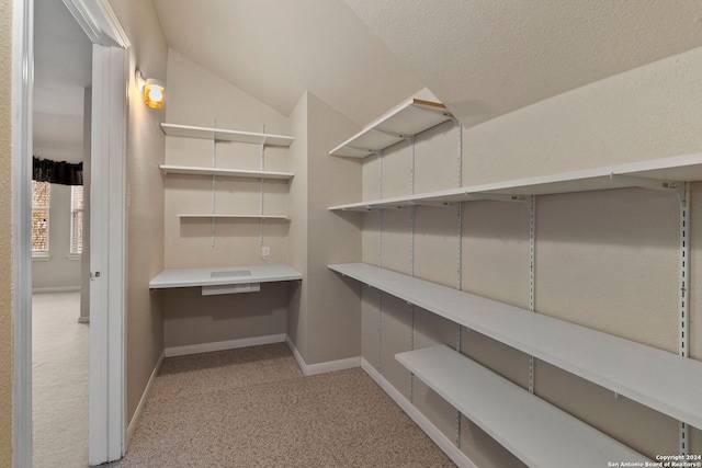 walk in closet with light carpet and vaulted ceiling