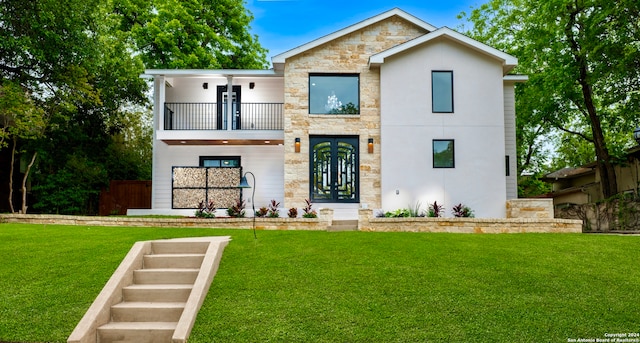 view of front of house with a front yard, a balcony, french doors, and stone siding