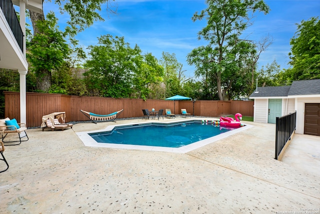 view of swimming pool featuring an outbuilding and a patio