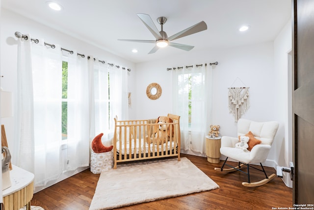 bedroom with dark hardwood / wood-style floors and a nursery area