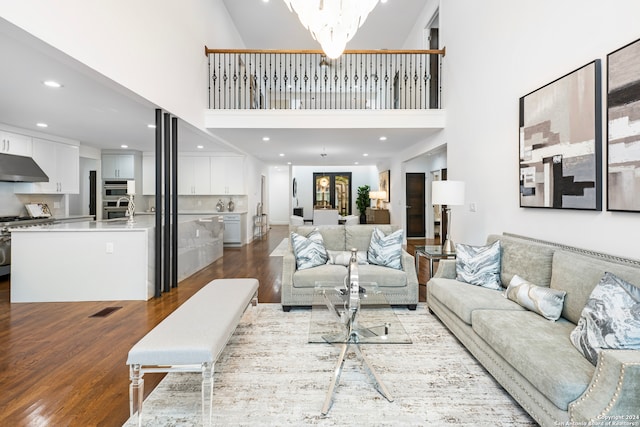 living room with hardwood / wood-style floors, an inviting chandelier, and high vaulted ceiling