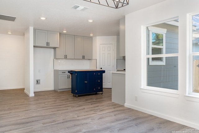 kitchen featuring decorative backsplash, a kitchen island, blue cabinetry, and light hardwood / wood-style flooring