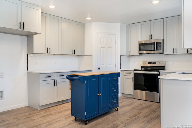 kitchen featuring decorative backsplash, light hardwood / wood-style floors, blue cabinets, and stainless steel appliances