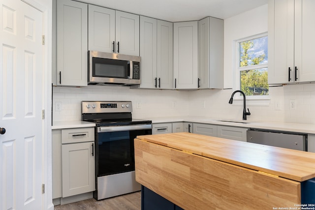 kitchen with decorative backsplash, light hardwood / wood-style floors, sink, and appliances with stainless steel finishes