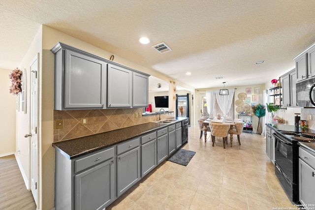 kitchen with black range, gray cabinets, decorative backsplash, and a textured ceiling