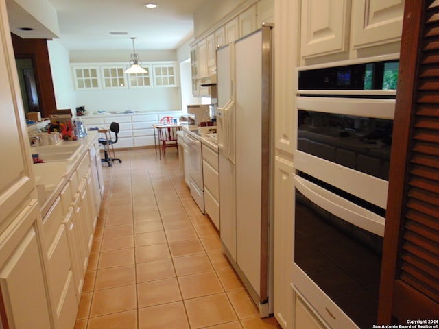 kitchen featuring white appliances, light tile patterned flooring, decorative light fixtures, and sink