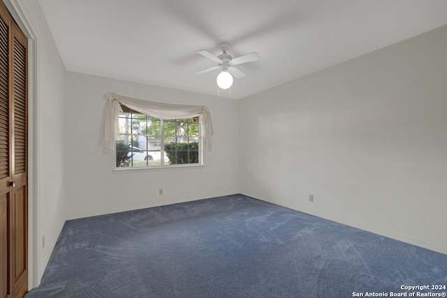 unfurnished bedroom with ceiling fan, a closet, and dark carpet