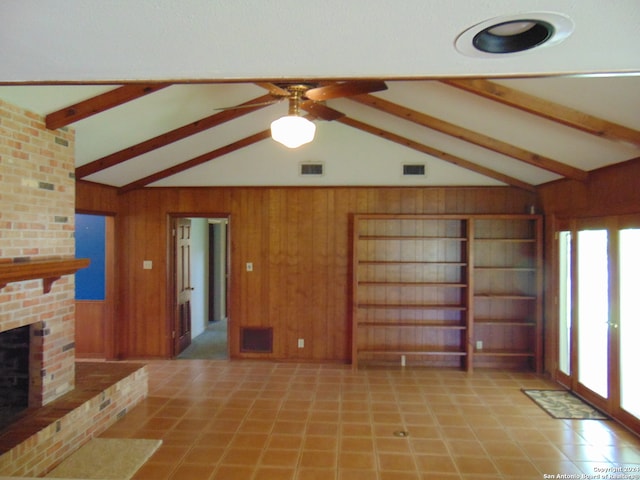 unfurnished living room featuring ceiling fan, french doors, a brick fireplace, vaulted ceiling with beams, and wooden walls