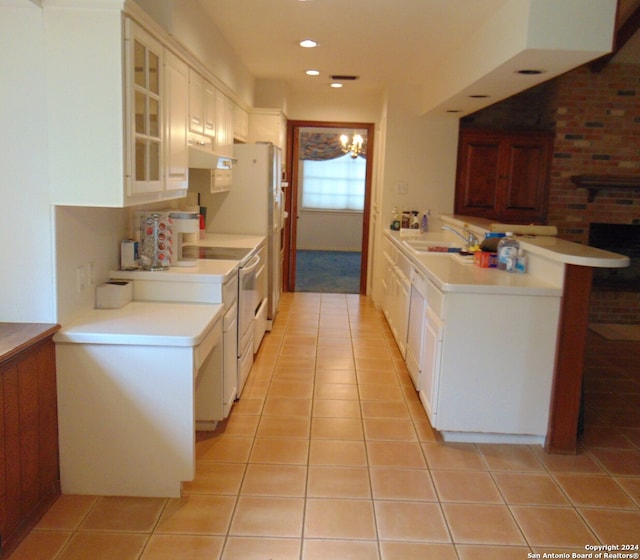 kitchen with white cabinetry, an inviting chandelier, kitchen peninsula, white appliances, and light tile patterned flooring