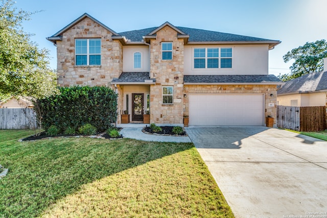 traditional-style home with a garage, driveway, fence, and a front lawn