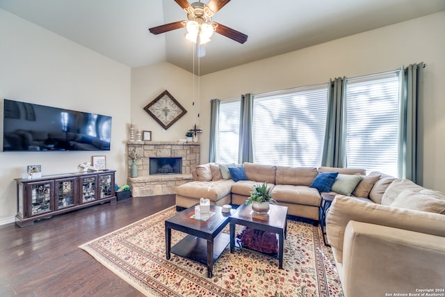 living room with lofted ceiling, ceiling fan, a stone fireplace, and wood-type flooring