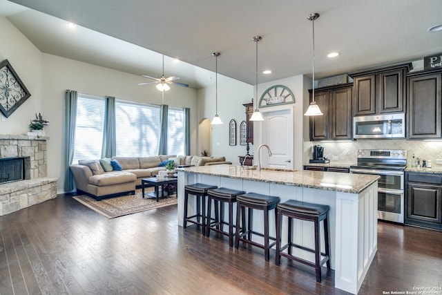 316 English Oaks Cir, Boerne, TX 78006 - kitchen with appliances with stainless steel finishes, a sink, open floor plan, a breakfast bar area, and light stone countertops