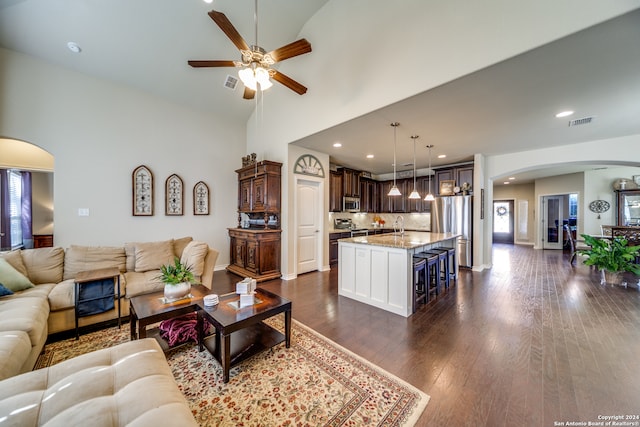 living room featuring dark hardwood / wood-style floors, ceiling fan, sink, and high vaulted ceiling